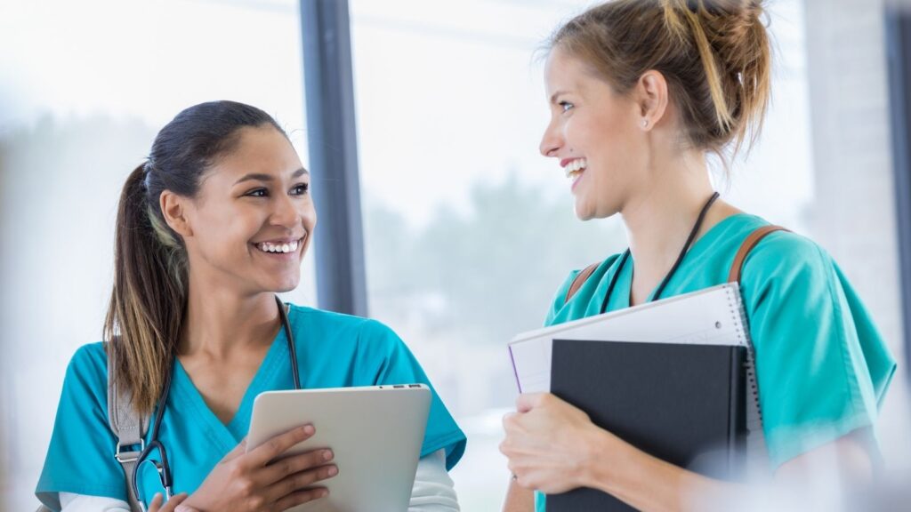 Friends travel nursing in pairs working together and smiling at each other.