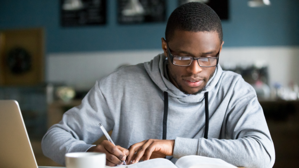 Male with glasses studying with coffee.