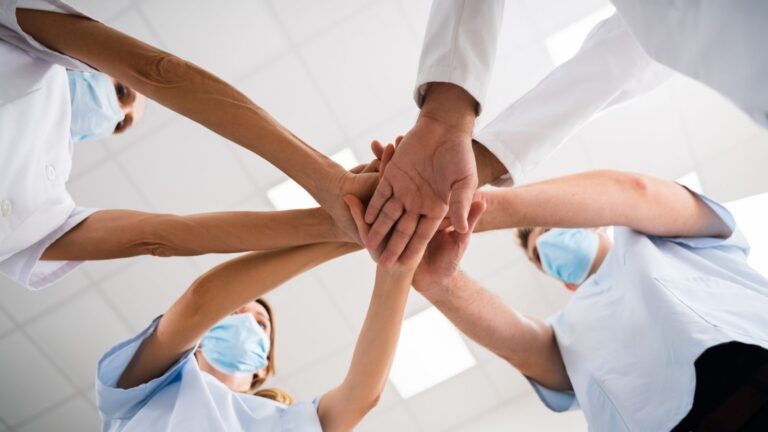 Travel nurse and allied health leaders hand-stacking in celebration of leadership qualities. Mental Wellness
