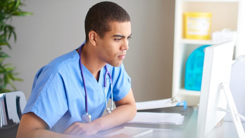 Male nurse looking at computer screen in an office.