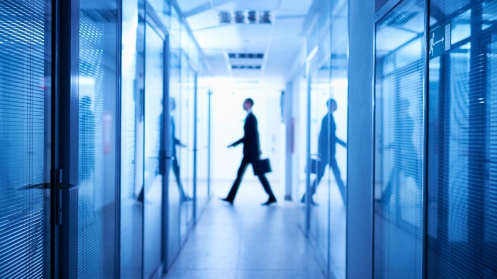 Man in suit walking across a hospital hall.
