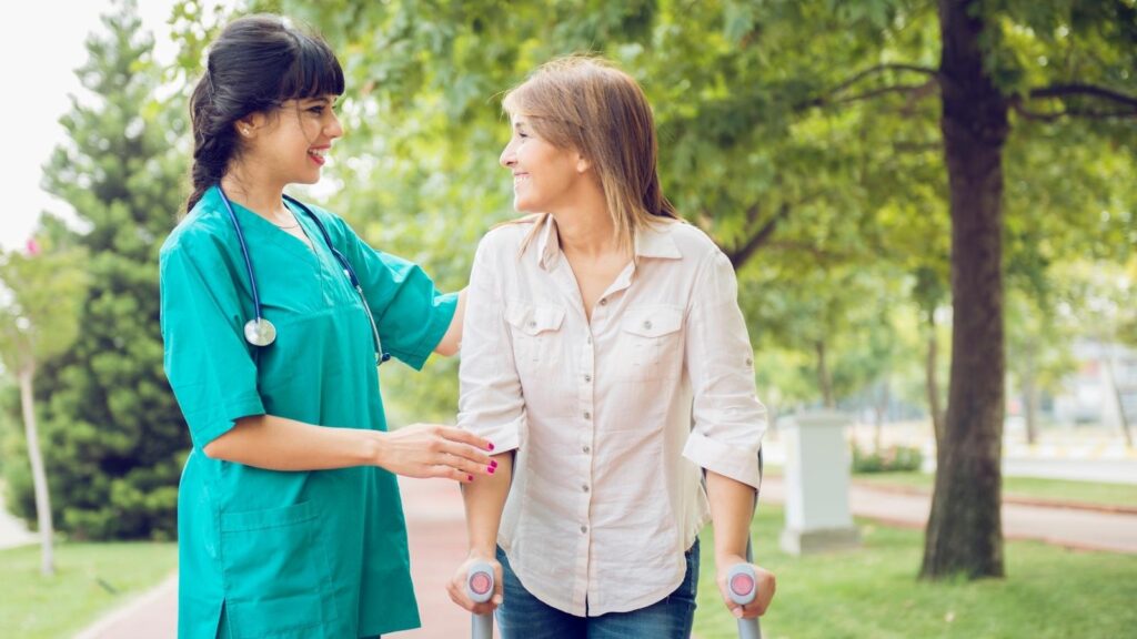 Allied health workers assisting a woman while walking outdoors.