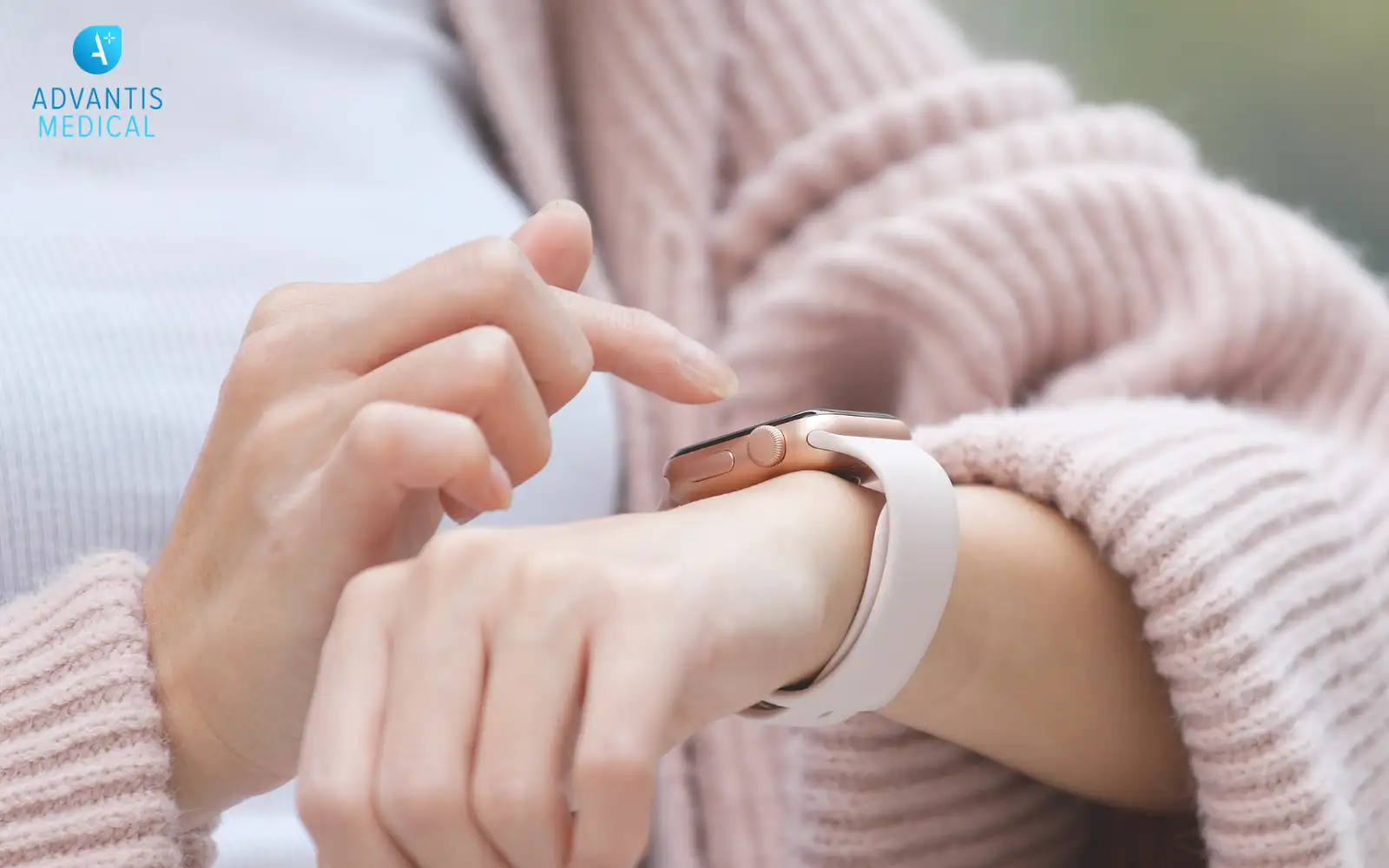 Female travel nurse wearing millenial pale pink and pointing at a smart watch on her wrist.