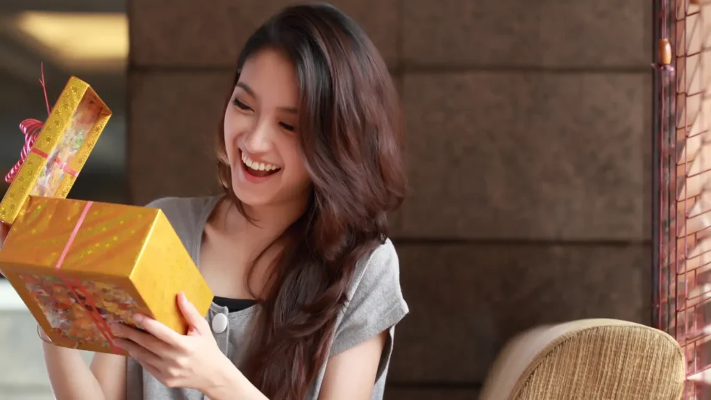 Young female travel nurse opening yellow present box and smilign excited at the gift.