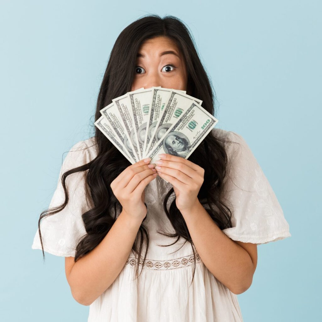 Traveler holding a fan of cash, representing housing stipend money